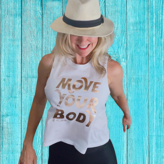 Girl jumping in a flowy white shirt with gold foil writing that says move your body - pilates shirt